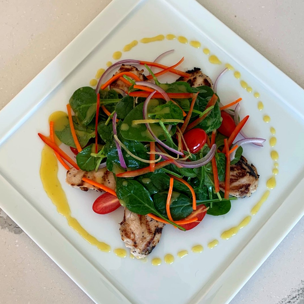 Grilled chicken salad with tomatoes, baby spinach, onion, carrots and lemon vinaigrette dressing